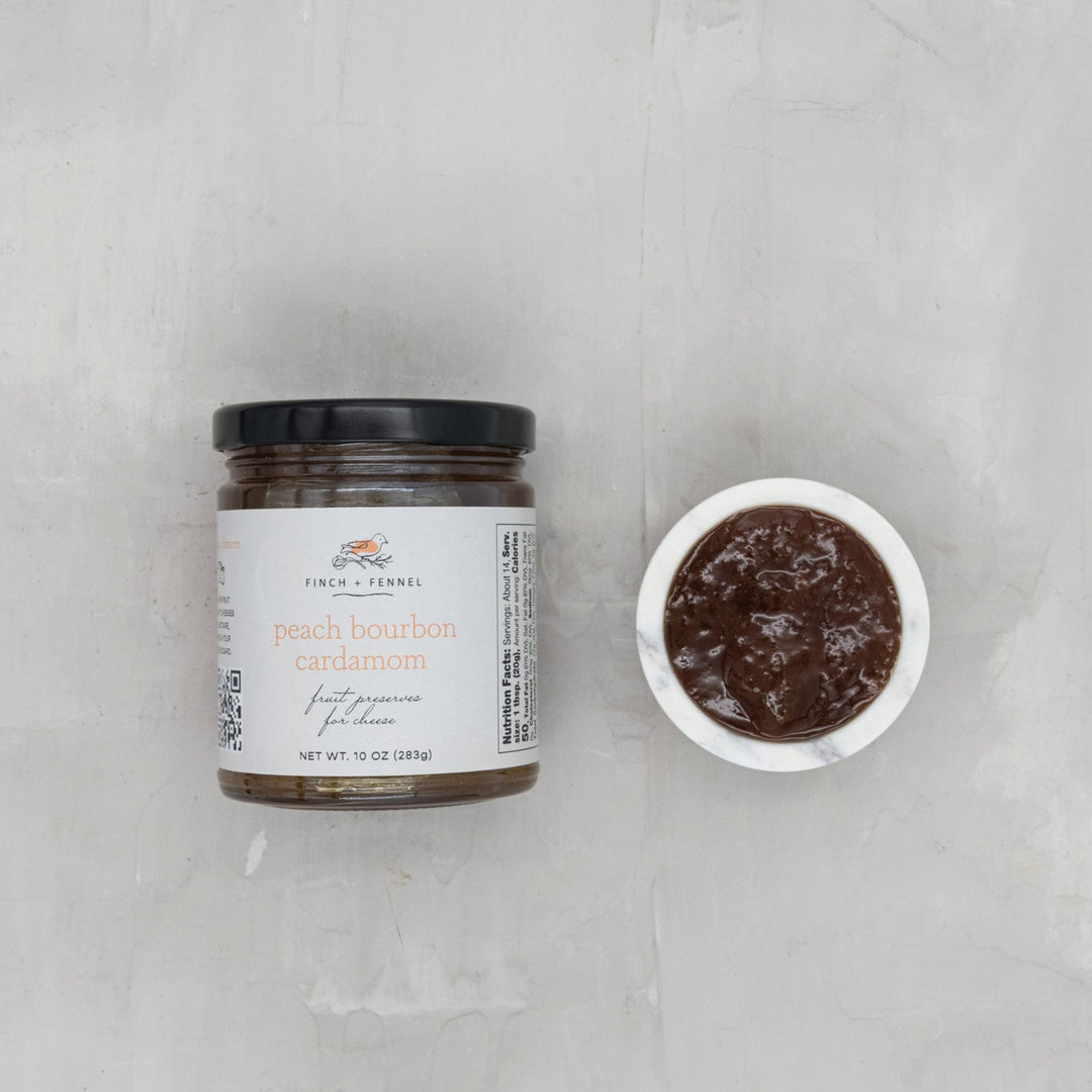 Jar of peach bourbon caramels with a small bowl of caramel on a light gray background