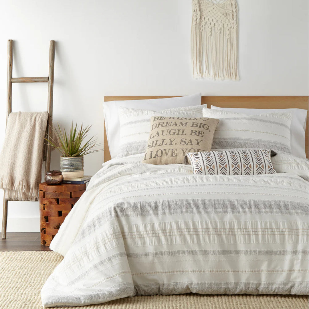 Neatly made bed with white bedding and decorative pillows in a bedroom setting.