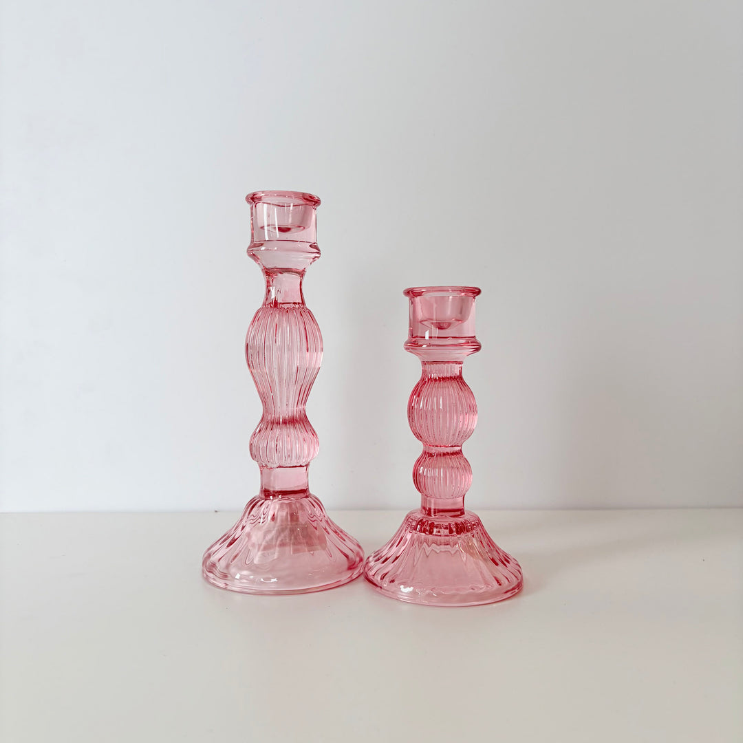 Two pink glass candle holders on a white background