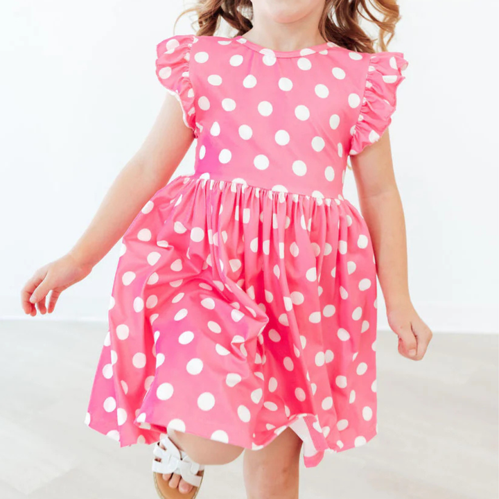 Child wearing a pink dress with white polka dots on a light background