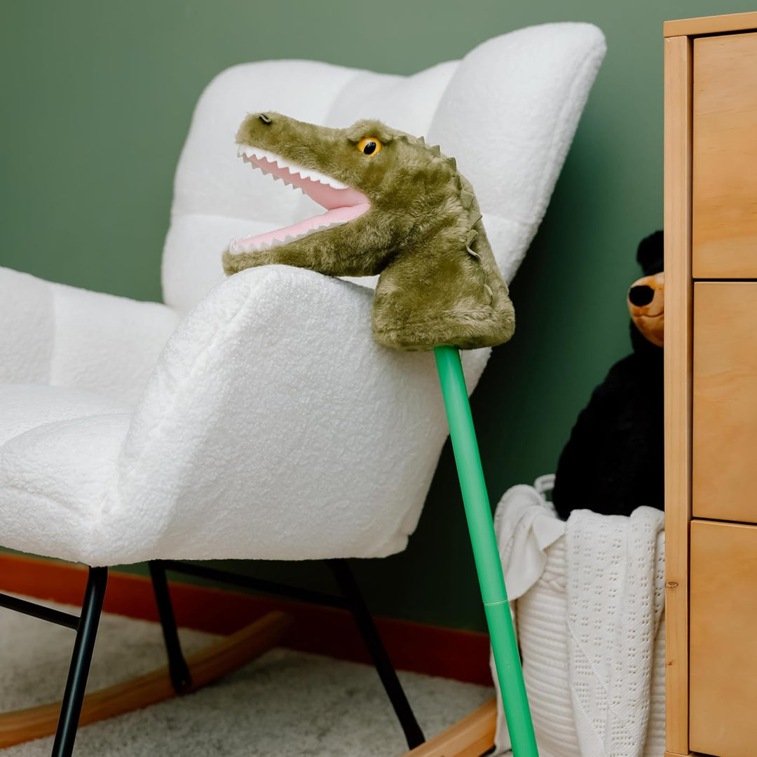 Plush toy alligator on a chair with a green wall and wooden cabinet in the background