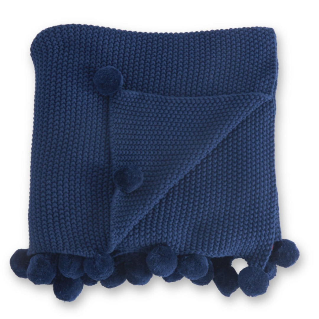 Blue knitted blanket with pom-pom trim on a white background