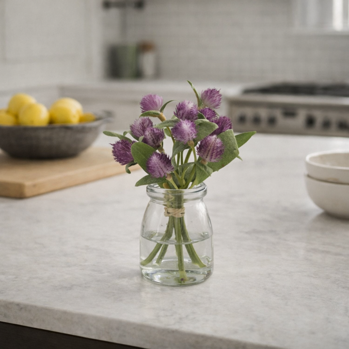 Clear glass vase with purple flowers on a kitchen counter
