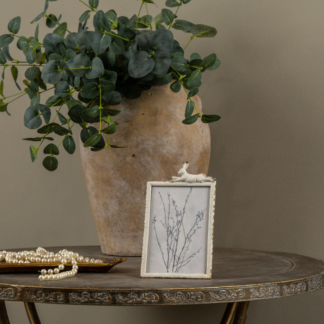 Decorative table with a vase, framed picture, and decorative items against a neutral background