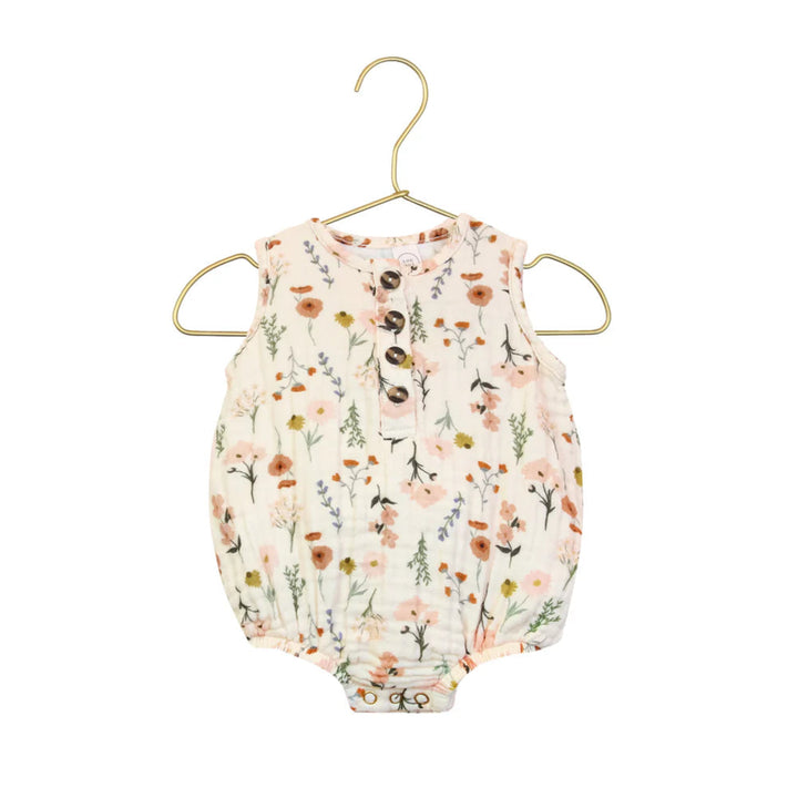 A sleeveless baby romper with a soft floral print, hanging on a gold metal hanger against a plain white background.