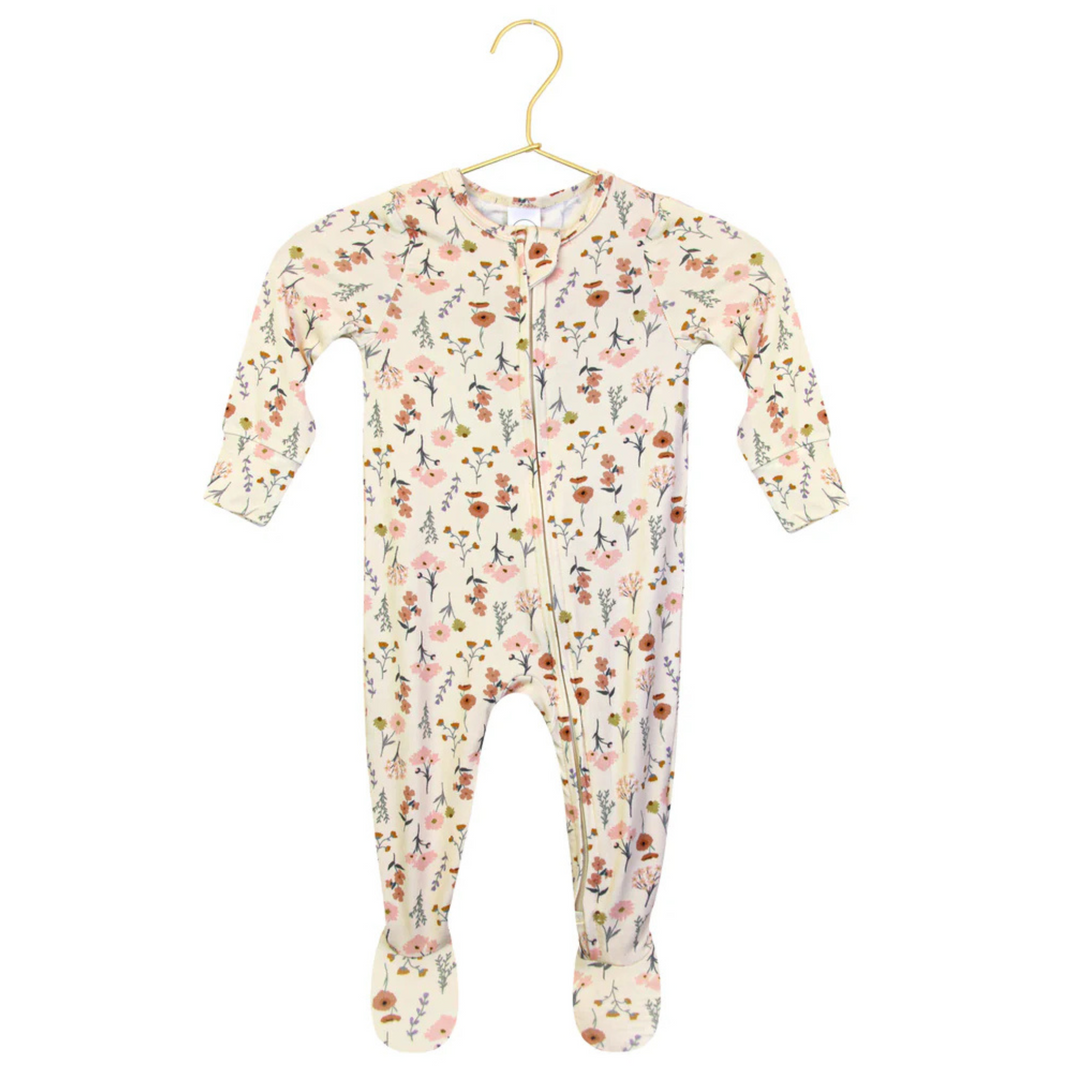 A baby footed sleeper with long sleeves and a front zipper, featuring an all-over floral print on a cream background. A circular inset in the bottom left corner provides a close-up of the floral pattern.