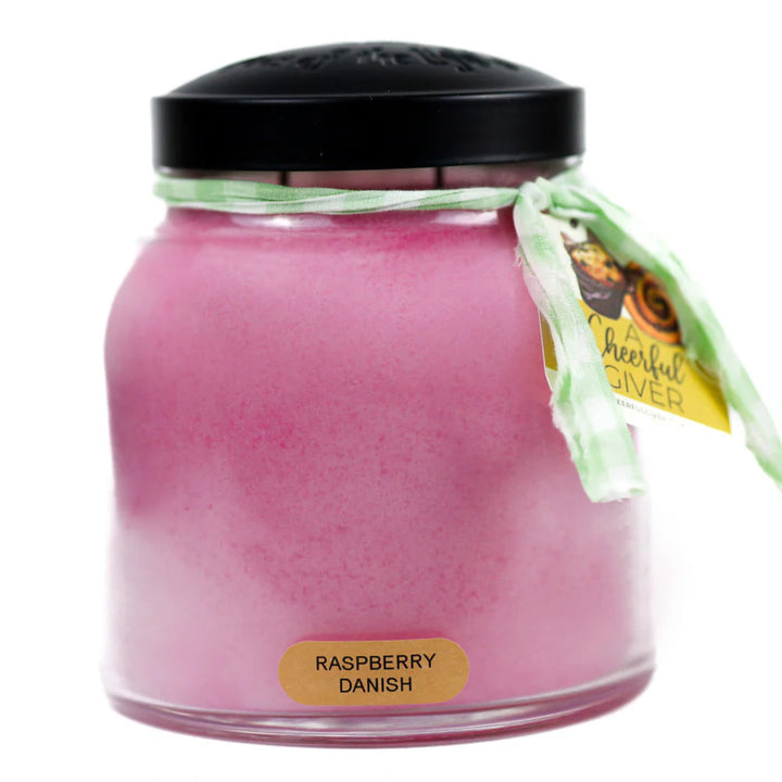Pink candle in a glass jar with a black lid and 'Raspberry Danish' label on a white background