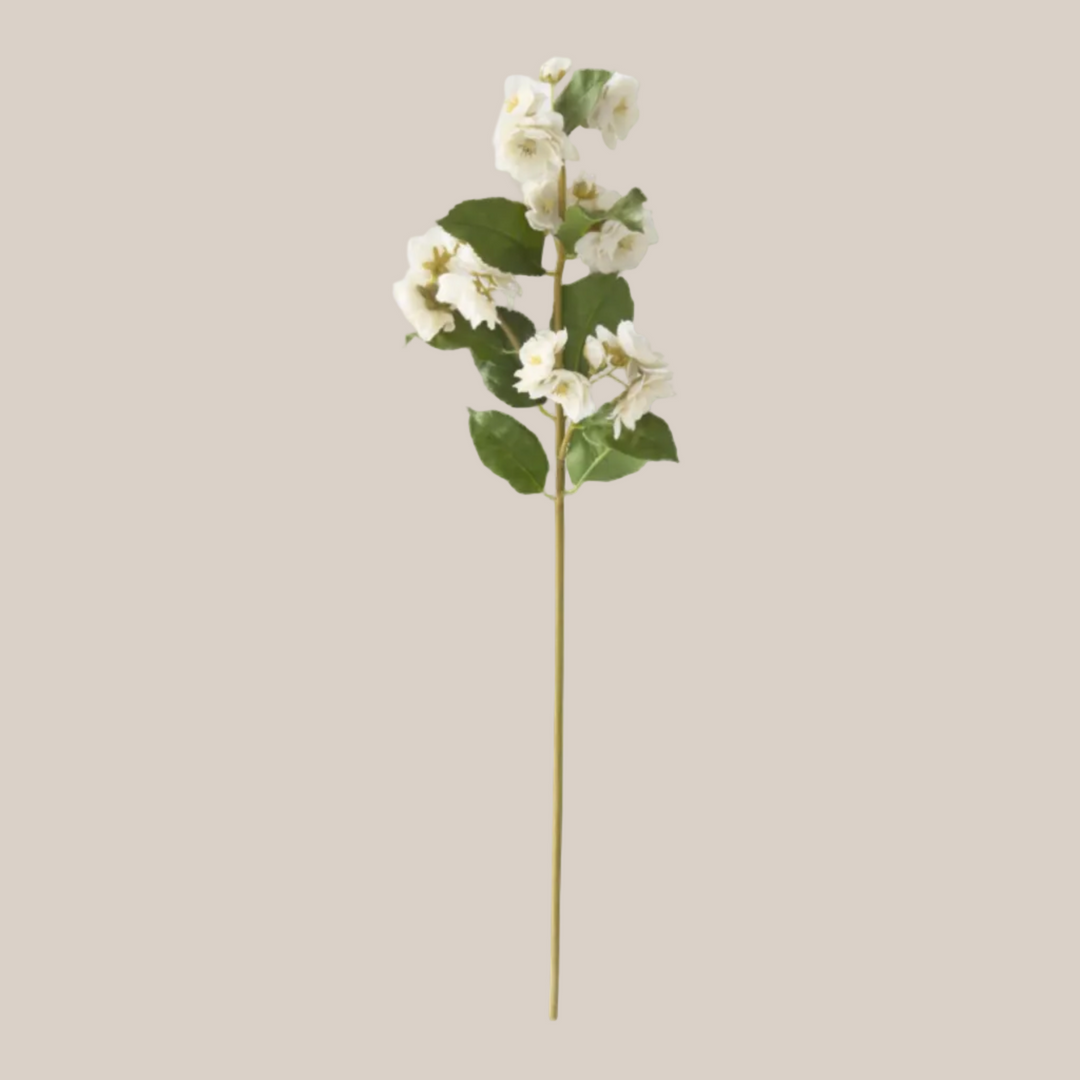 Artificial flower stem with white flowers and green leaves on a white background
