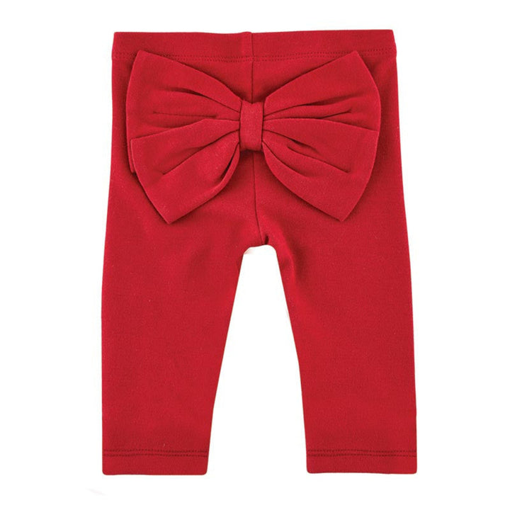 Red toddler leggings featuring a large, oversized fabric bow at the waistband, shown flat against a solid white background.