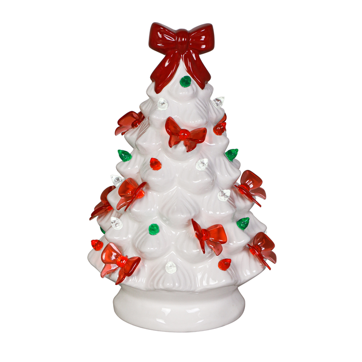 A white ceramic Christmas tree figurine decorated with red bows, red ornaments, and small green accents, set against a plain white background.