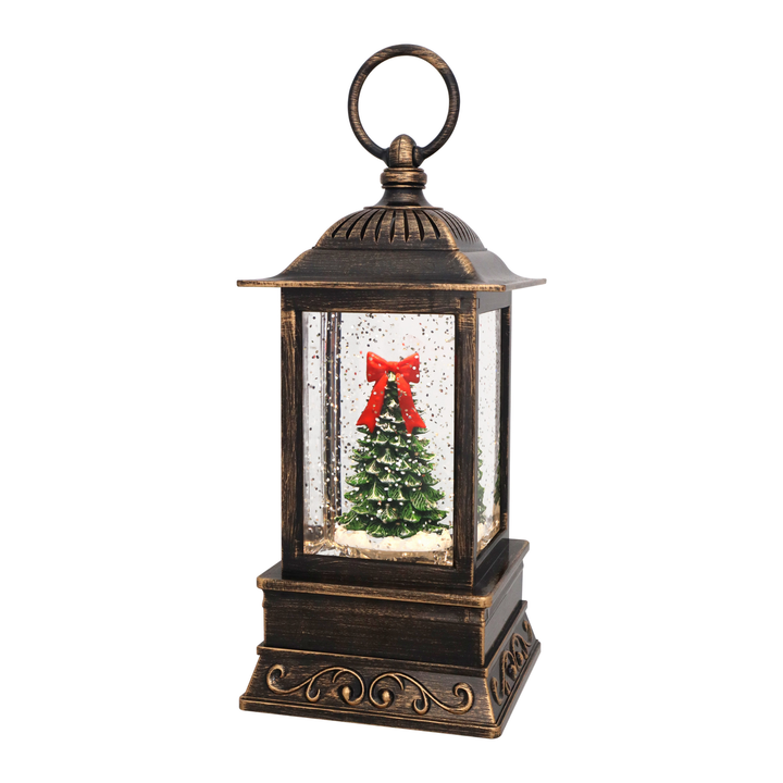 A decorative lantern-style Christmas tree snow globe with an antique bronze finish, featuring a miniature green Christmas tree with a red bow inside clear glass panels on a white background.