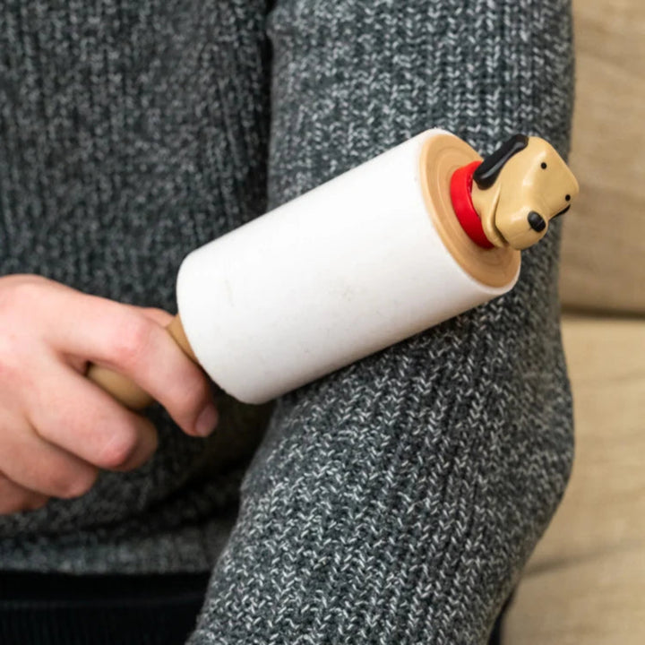 Person holding a dog-shaped lint roller against a neutral background