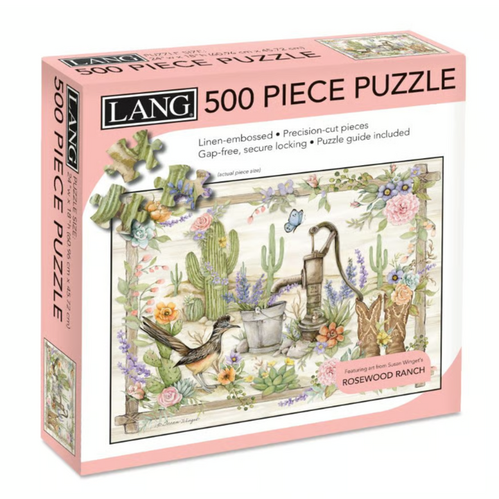 Lang 500-piece jigsaw puzzle box titled 'Rosewood Ranch', featuring a pink border and an illustrated scene of cacti, a watering can, a bird, and a cowboy boot.