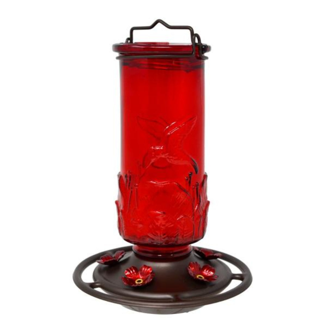 Red glass hummingbird feeder with black metal base on a white background