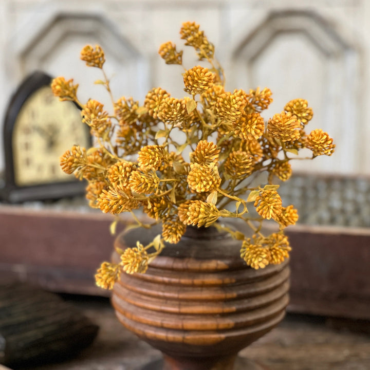 Wooden vase with yellow flowers on a wooden surface