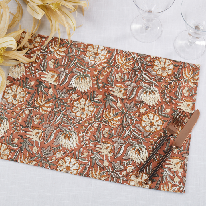 Floral patterned placemat with cutlery on a white surface