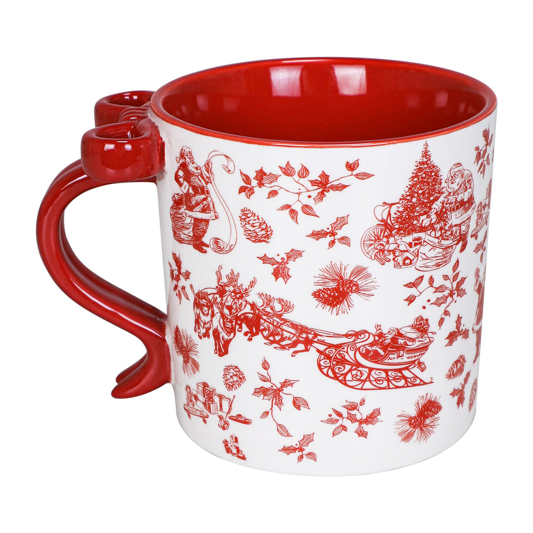 A white ceramic mug with a glossy red interior, red handle, and red holiday-themed toile pattern featuring Santa Claus, sleighs, pine trees, and floral motifs.