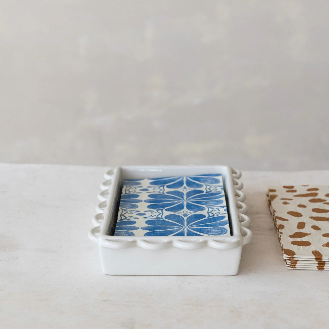 Set of playing cards with blue and white design in a white holder on a light surface.