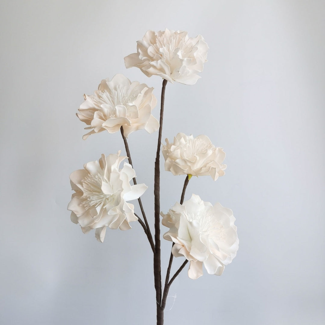 Artificial white flower branch on a plain background