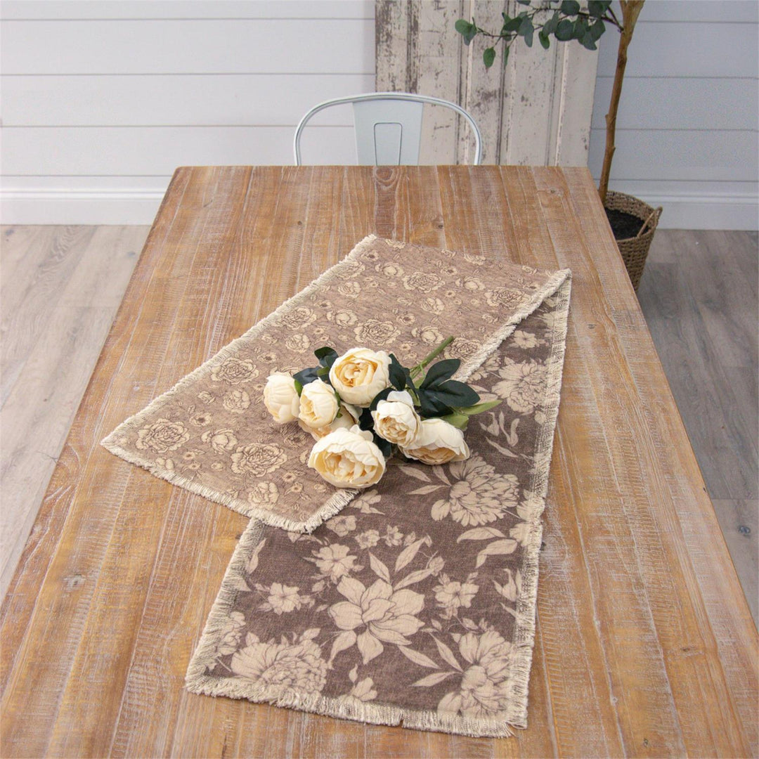 Floral-patterned table runner on a wooden table with white flowers.