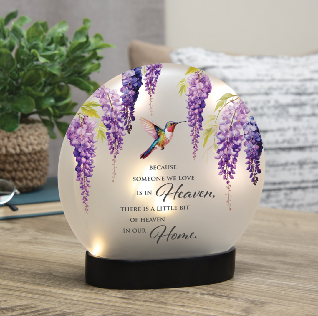 Decorative lamp with wisteria flowers and a hummingbird on a wooden surface.