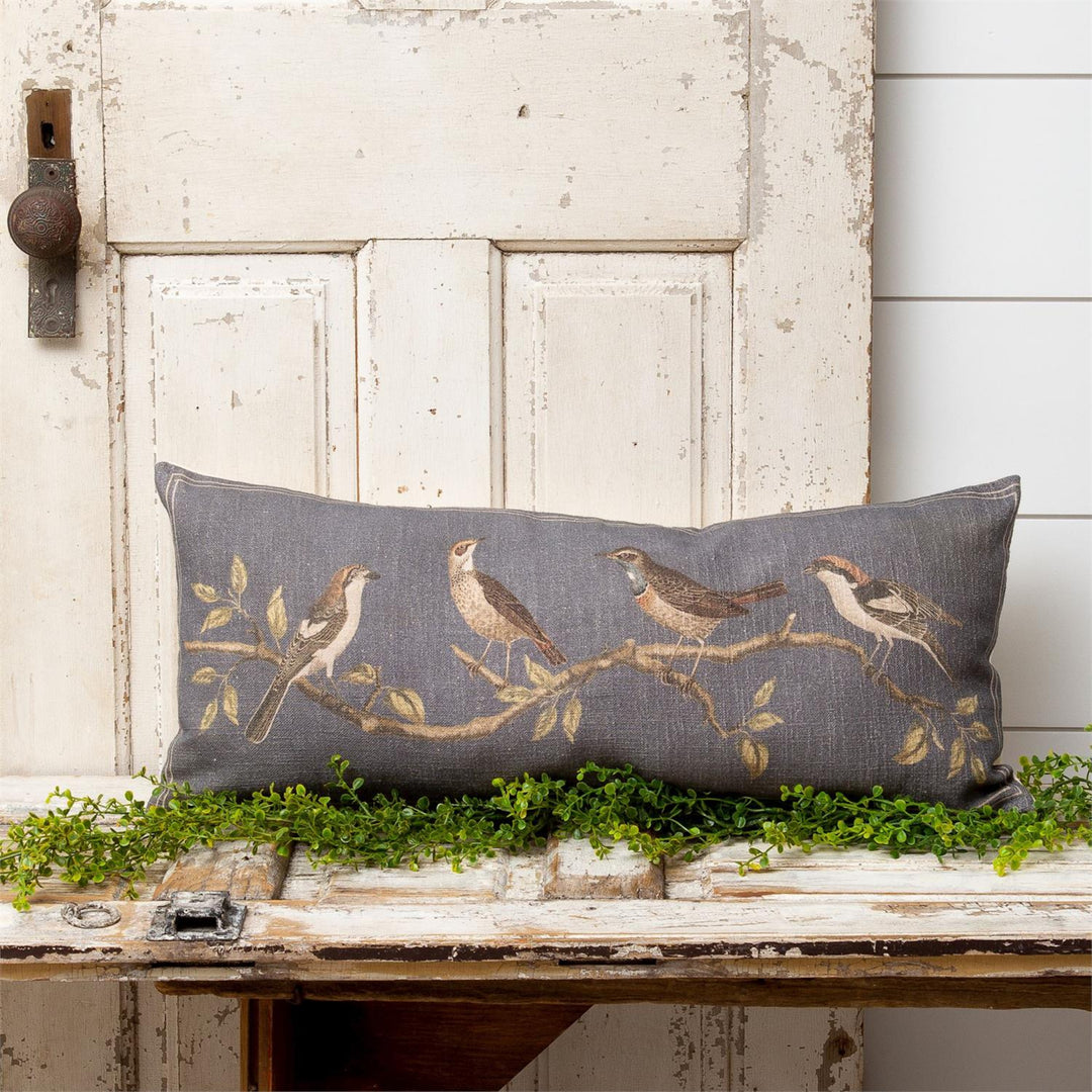 Decorative pillow with bird design on a rustic wooden surface