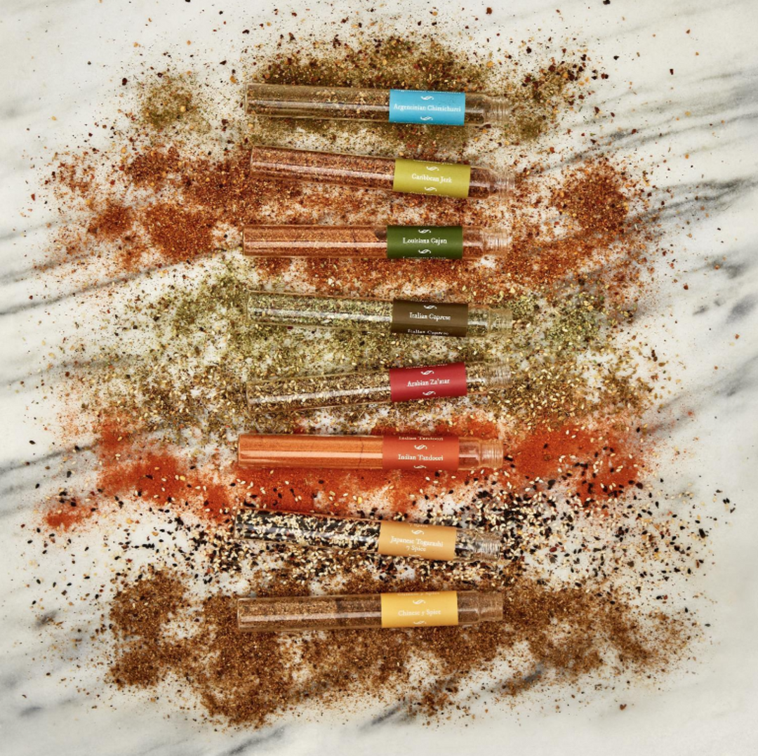 Set of small glass containers with colorful lids on a marble surface with spice撒落
