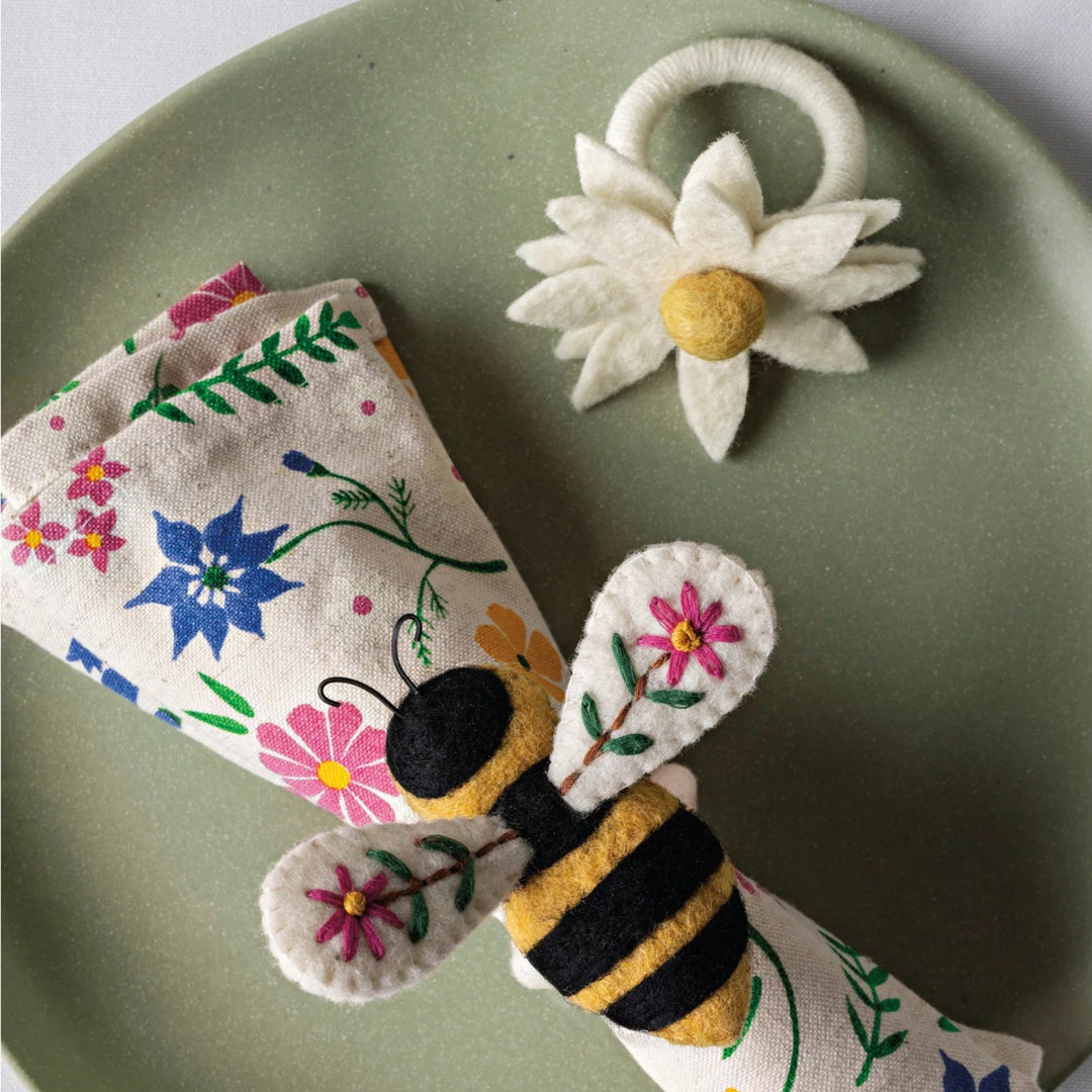Felt bee, flower, and butterfly on a green plate with a white background