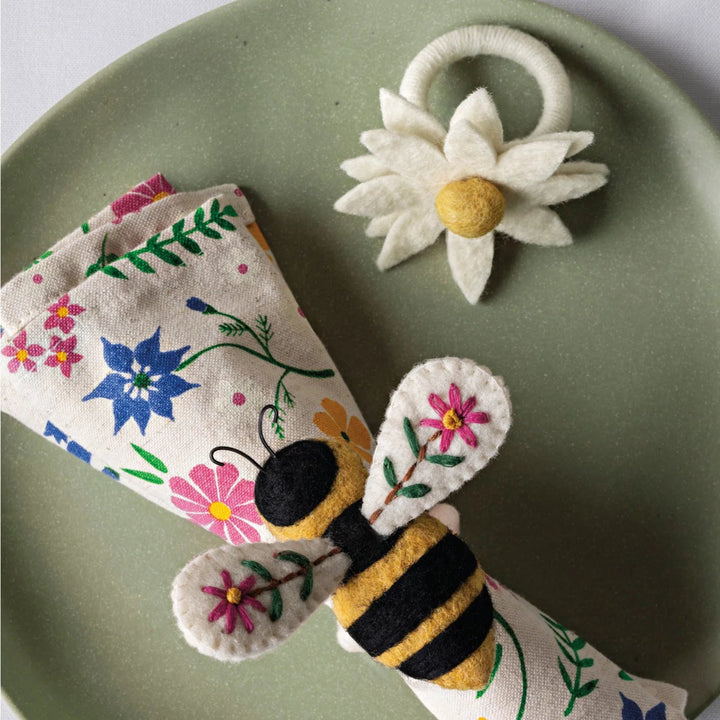 Felt bee, flower, and butterfly on a green plate with a white background
