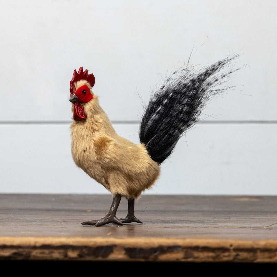 Rooster toy standing on a wooden surface with a light gray background