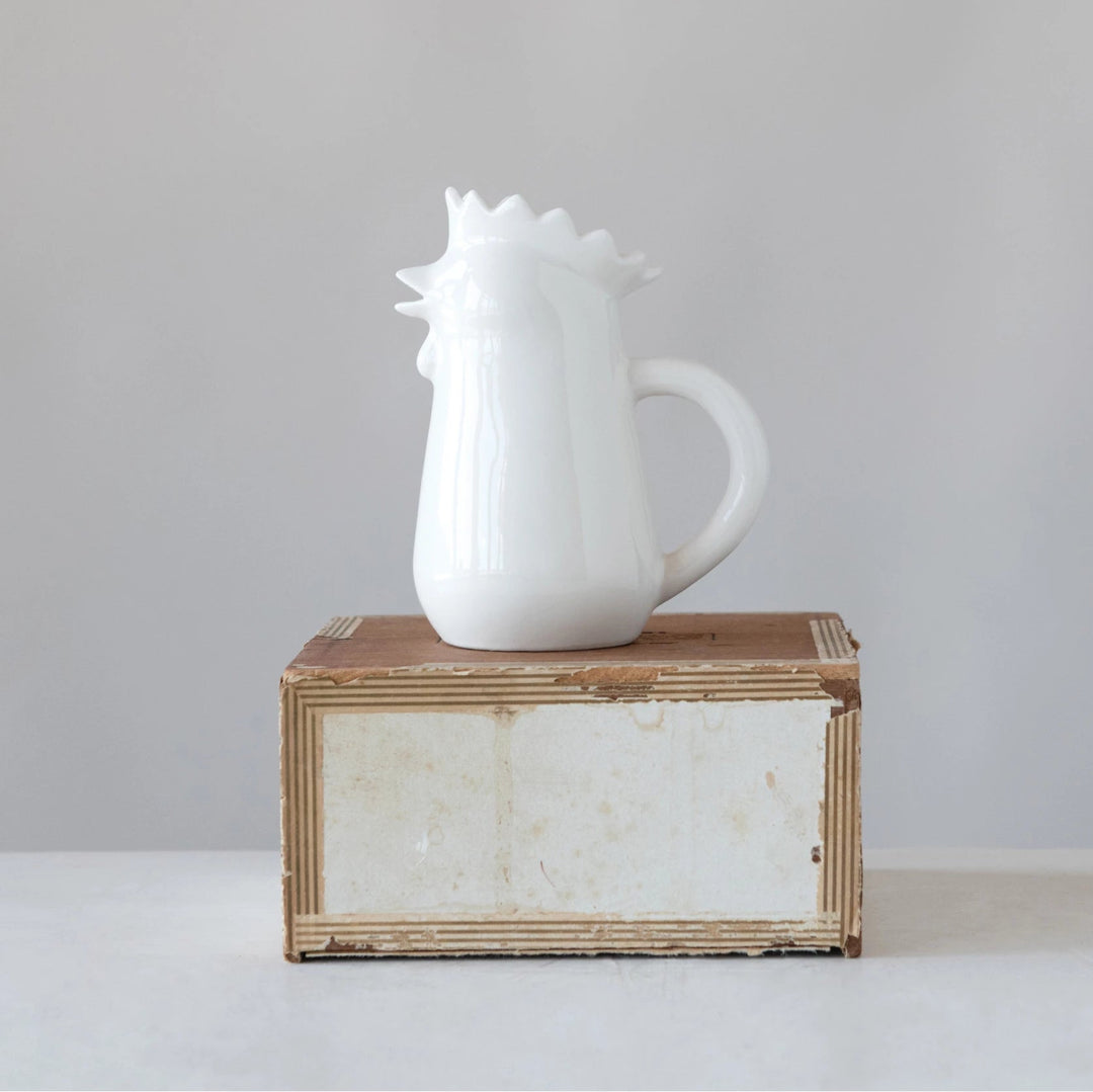 White ceramic pitcher on a wooden block with a plain background