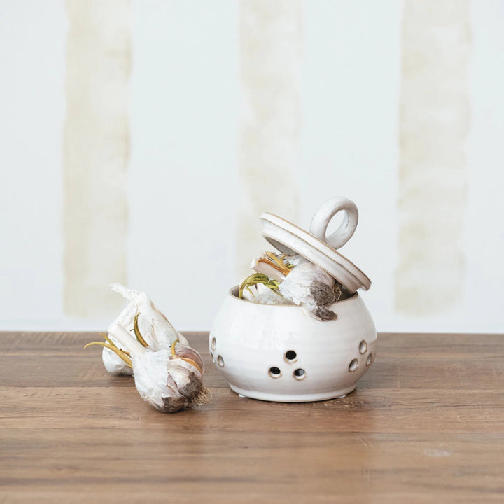 White ceramic pot with garlic inside on a wooden surface