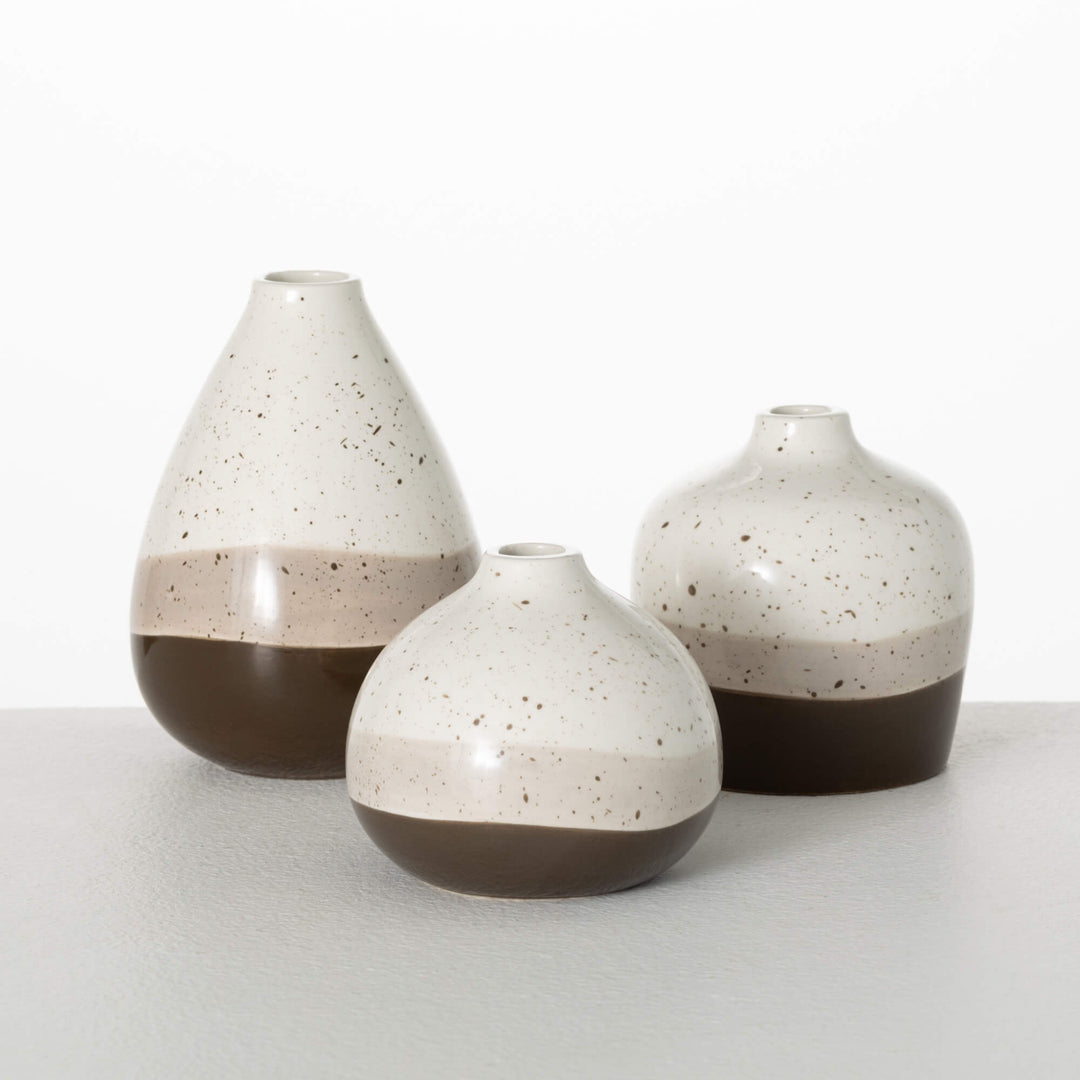 A set of three ceramic vases with a speckled pattern, in brown, white, and beige colors, in varying sizes placed next to each other.