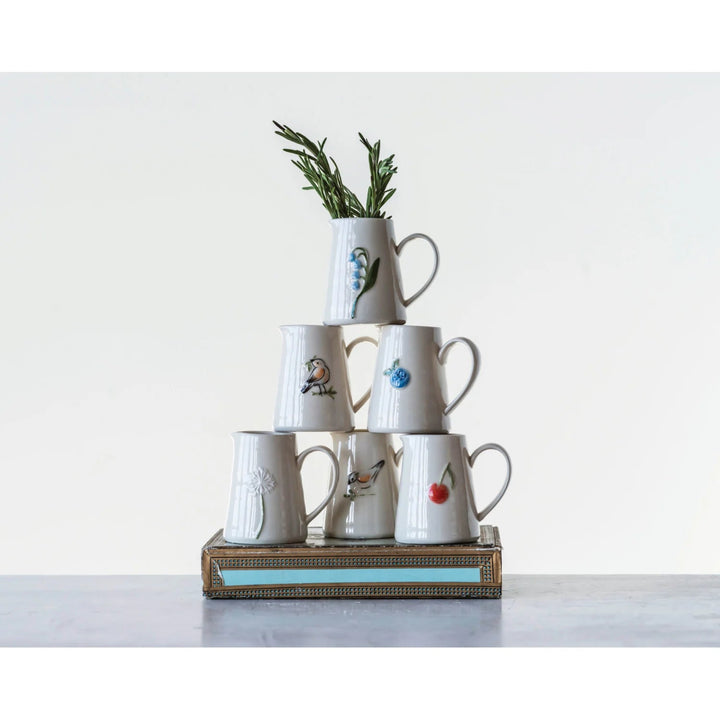 Stack of white mugs with various designs on a white background