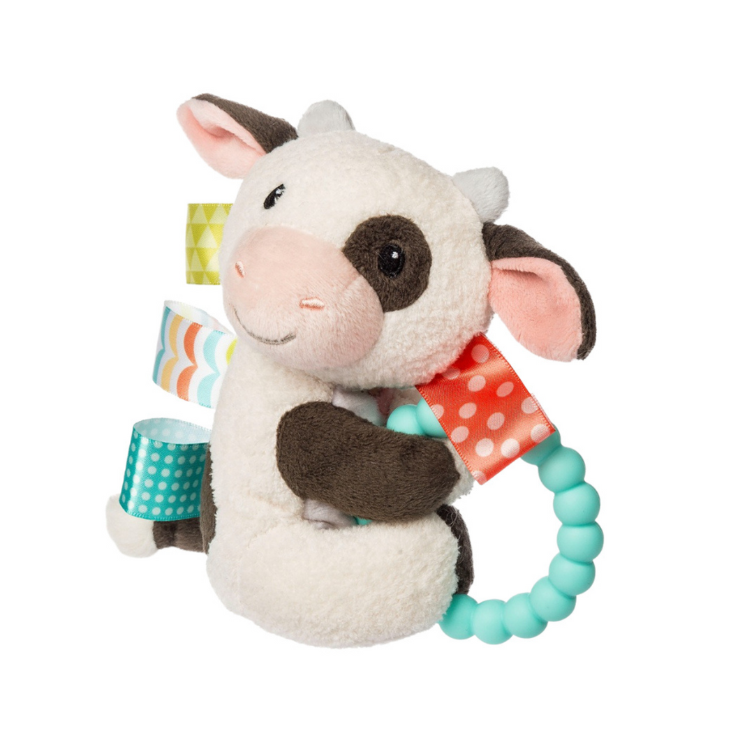 Plush cow toy with teething ring on a white background