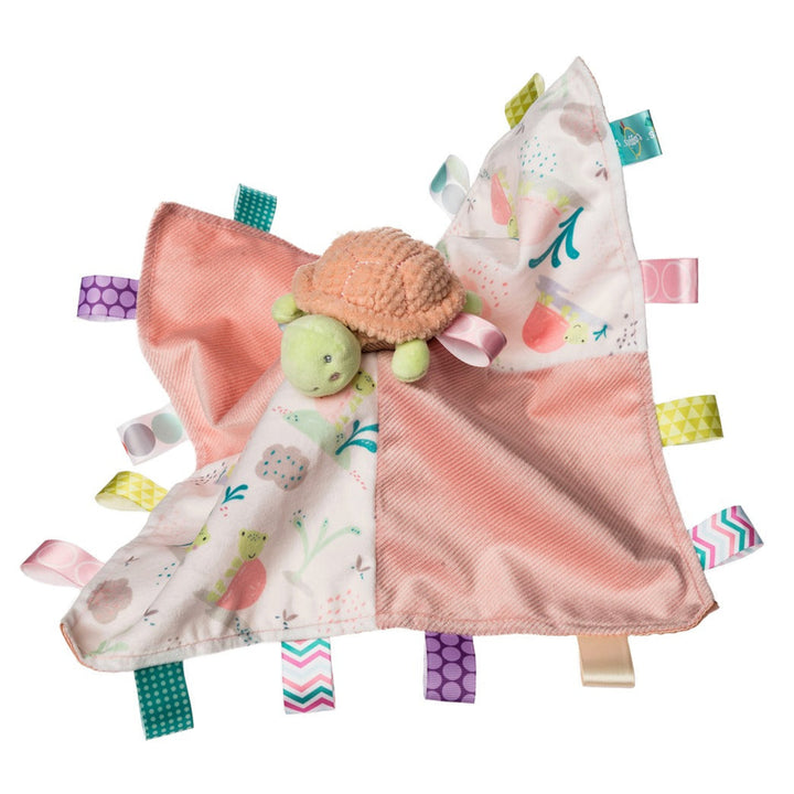 Baby comfort blanket with turtle toy and colorful tags on a white background