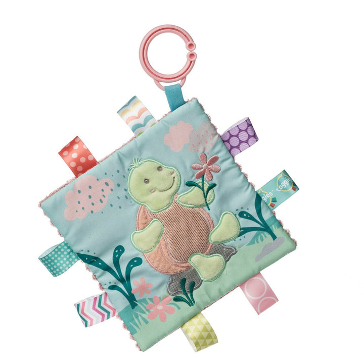 Baby comfort blanket with turtle design and colorful tags on a white background