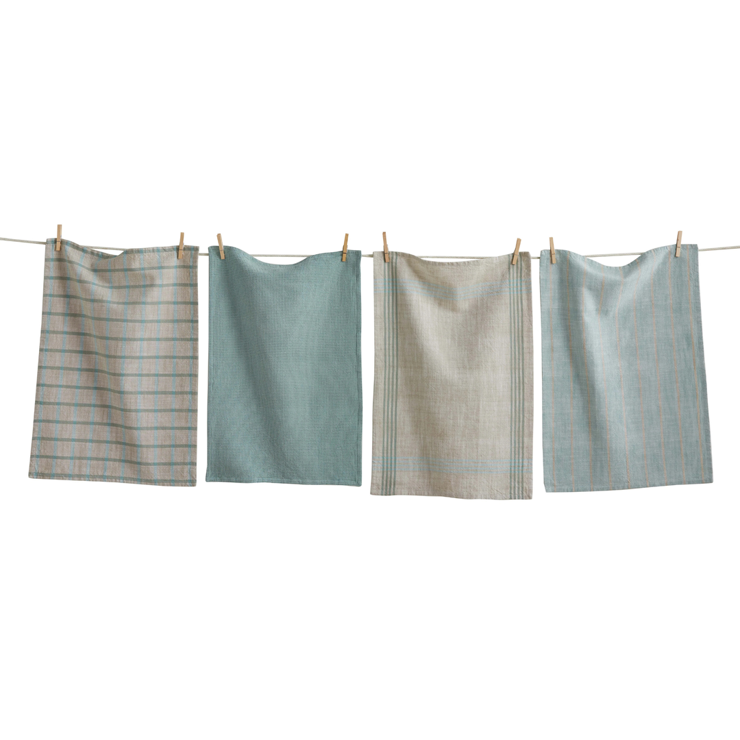 Four towels of different patterns hanging on a clothesline against a white background