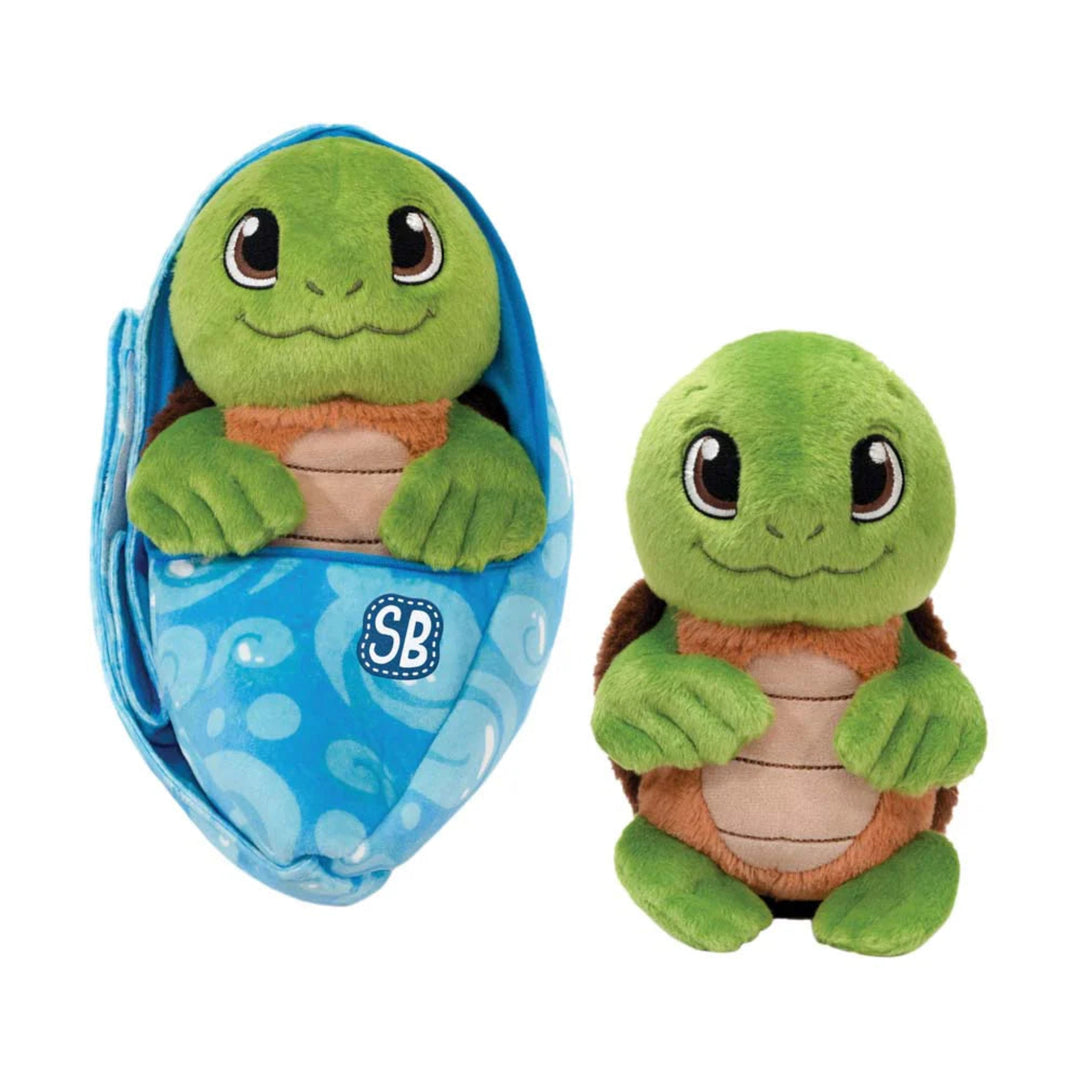 Green plush turtle toy with brown shell next to its blue packaging on a white background