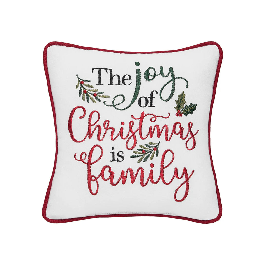 Decorative pillow with 'The joy of Christmas is family' text and holly leaves on a white background