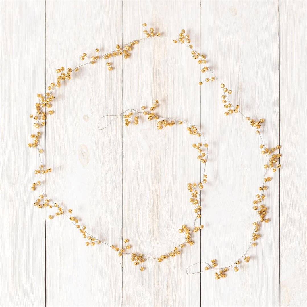 A decorative garland of small golden-yellow berries or dried floral clusters arranged in a loose circle on a white wooden plank background.
