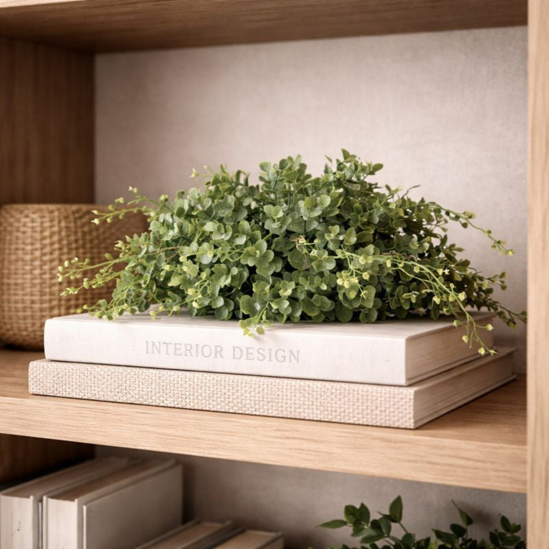 Stack of books with a plant on top on a wooden shelf