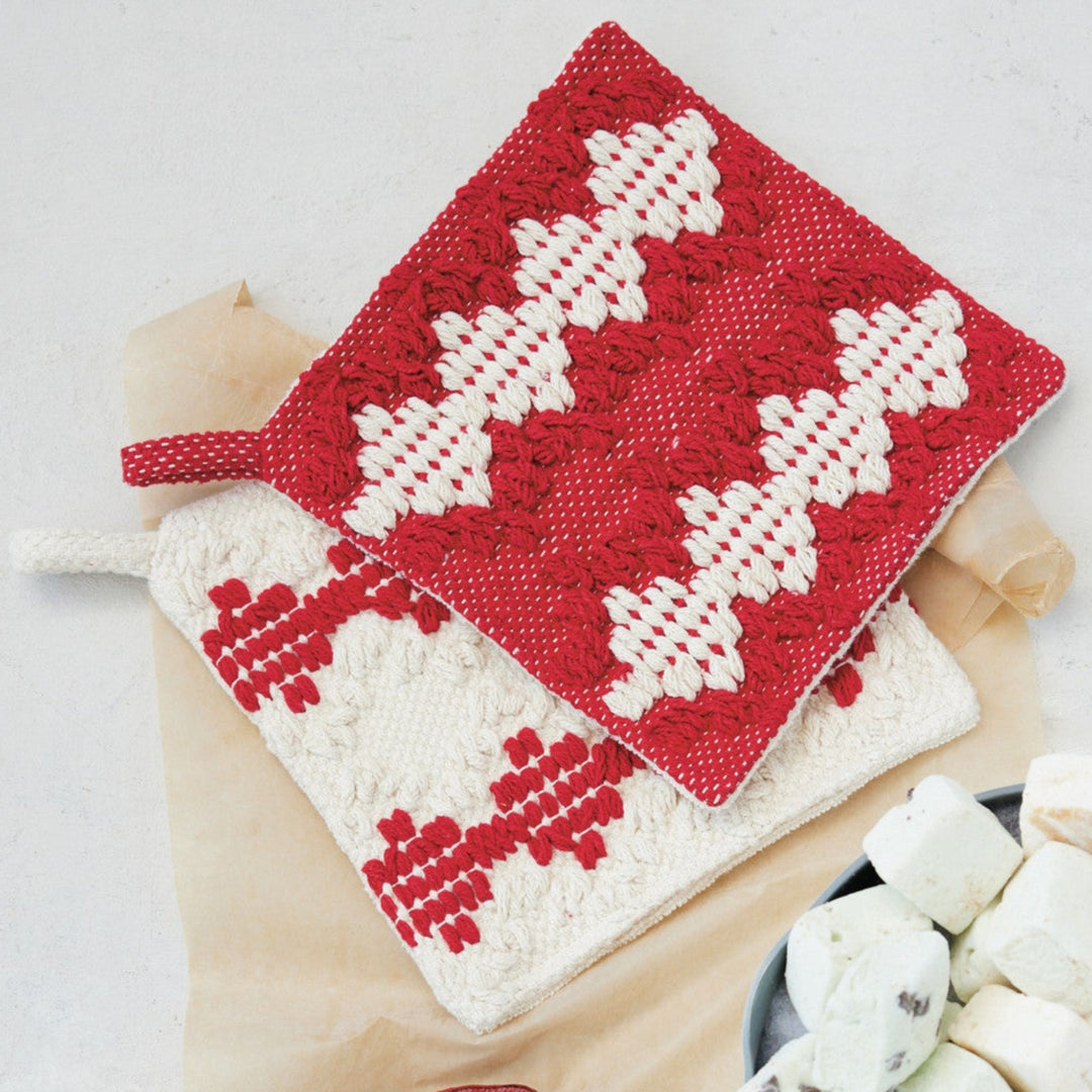 Red and white cross-stitched fabric, Santa cookie cutter, and bowl of marshmallows on a light background
