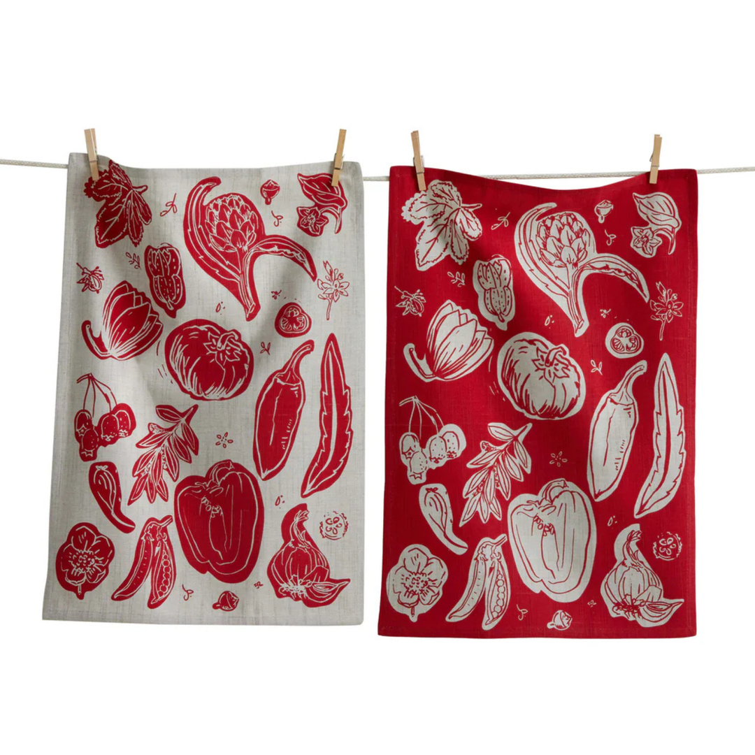Two kitchen towels with red and white vegetable patterns hanging on a line.