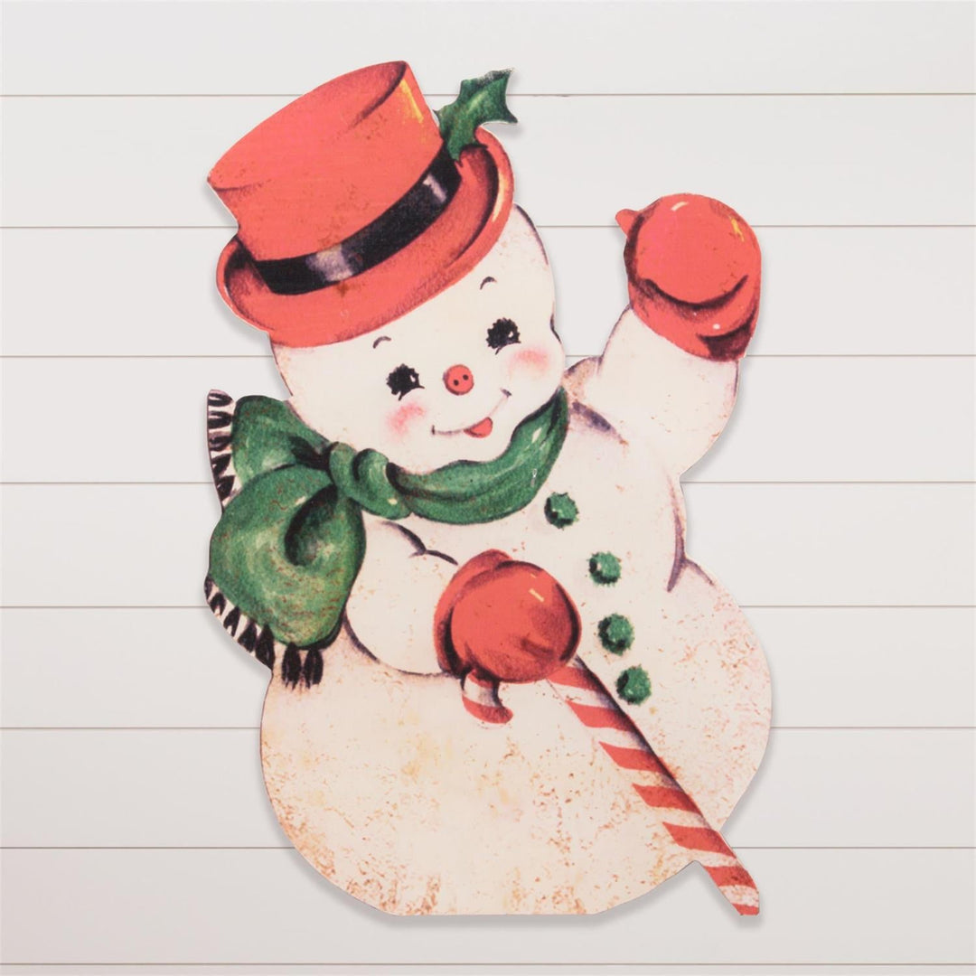 Vintage-style paper snowman decoration with a red hat and green scarf on a wooden surface.