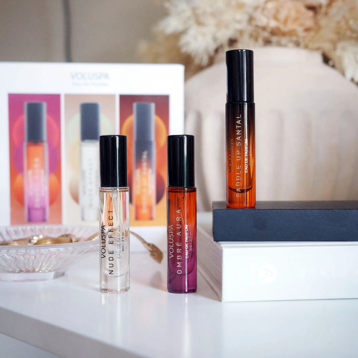 Three perfume bottles on a table with a decorative background