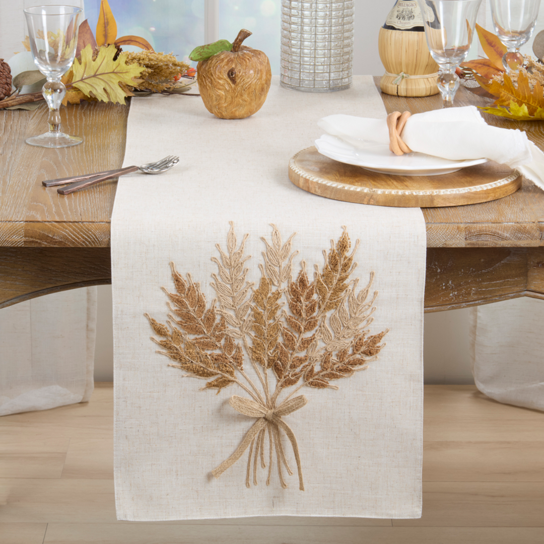 Table setting with a decorative table runner featuring a wheat bundle design.