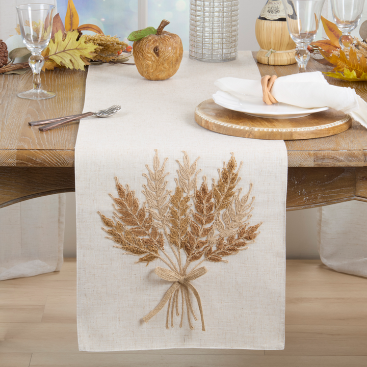 Table setting with a decorative table runner featuring a wheat bundle design.
