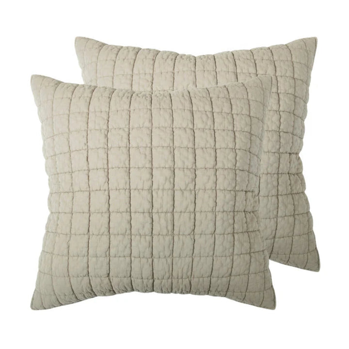 Two square quilted throw pillows in a light beige fabric, arranged with one slightly behind the other on a plain white background.