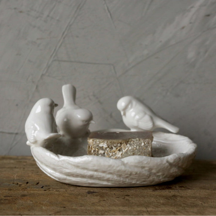 Decorative ceramic dish with bird designs on a wooden surface and gray background